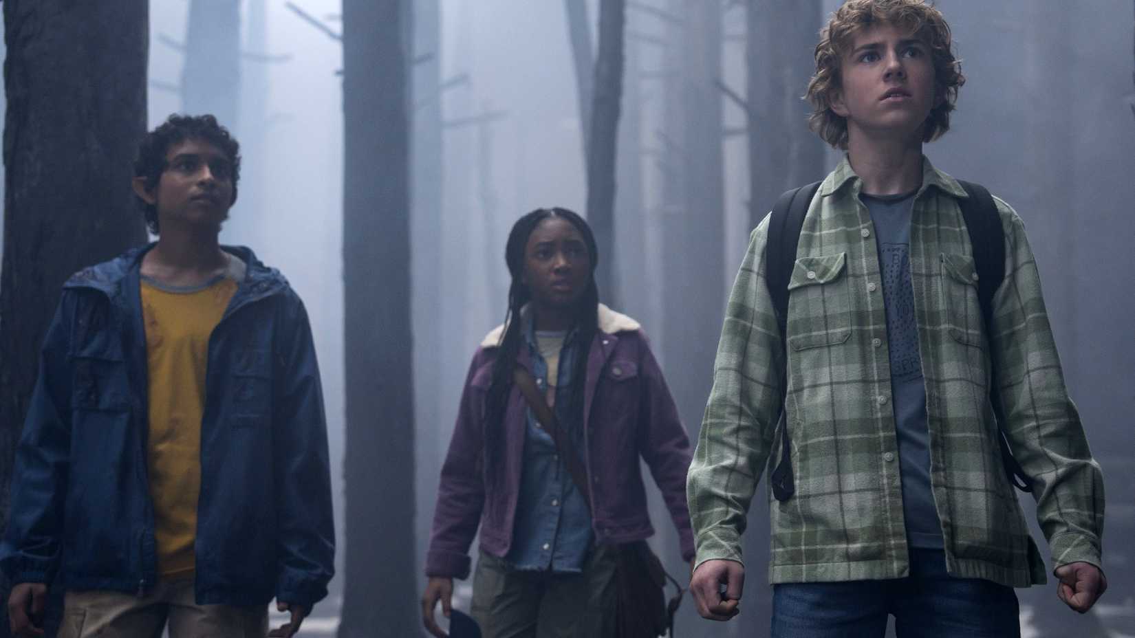 Aryan Simhadri as Grover, Leah Sava Jeffries as Annabeth Chase, and Walker Scobell as Percy Jackson stand together in the woods.