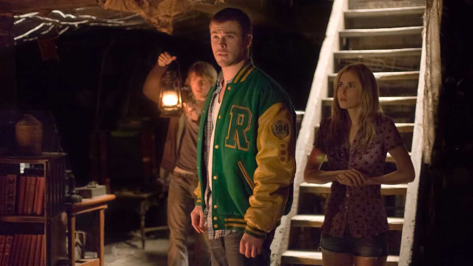 Chris Hemsworth, Anna Hutchinson e Fran Kranz explorando o porão em O Segredo da Cabana