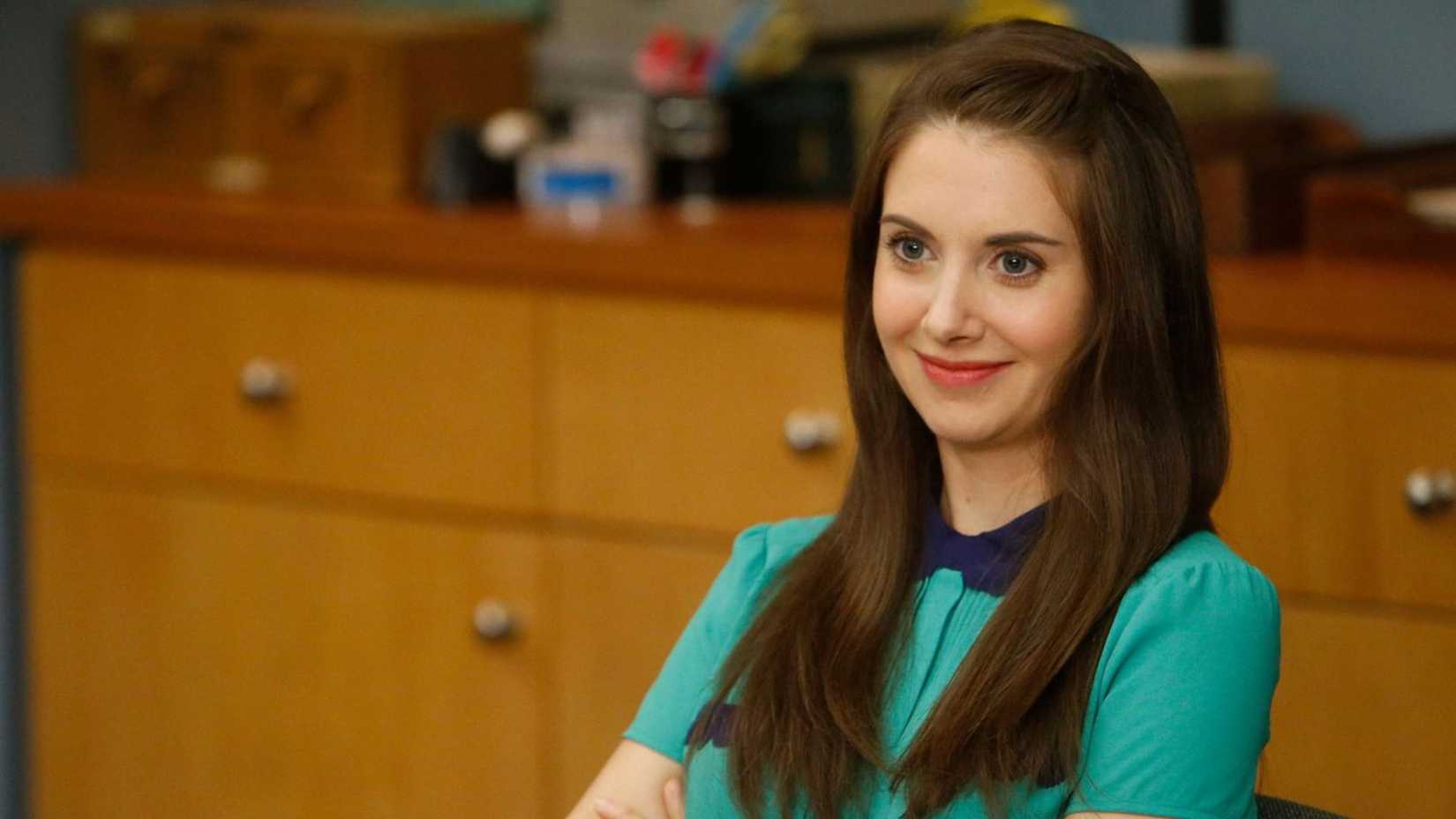 Annie smiles while crossing her arms in the study room in Community