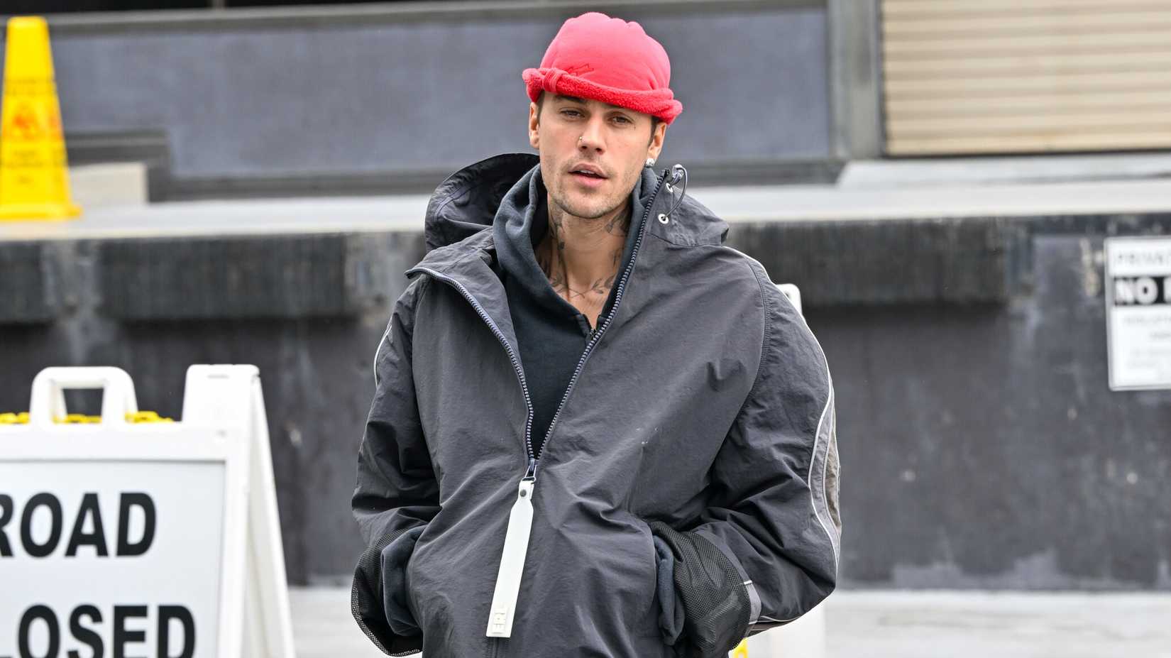 Justin Bieber trägt auf dem Paparazzi-Foto eine rote Mütze und einen grauen Mantel.
