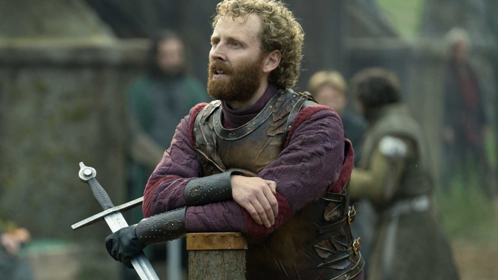 Edward Ashley apoiado com uma espada em A Cavaleiro dos Sete Reinos