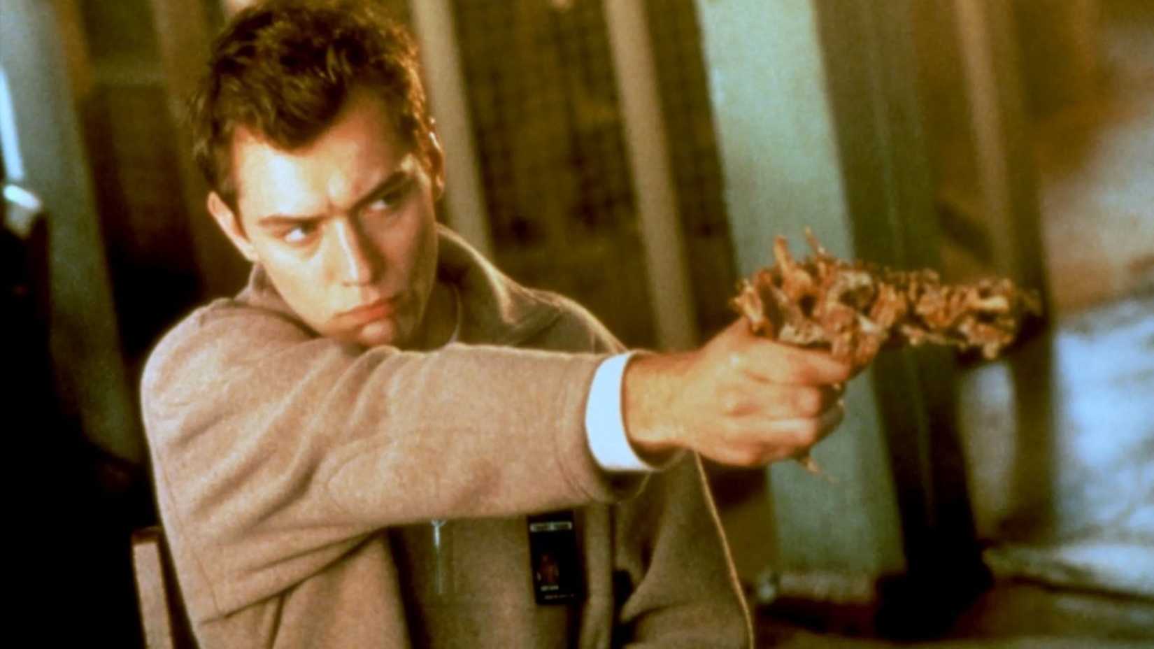 Jude Law aponta uma arma estranha em eXistenZ