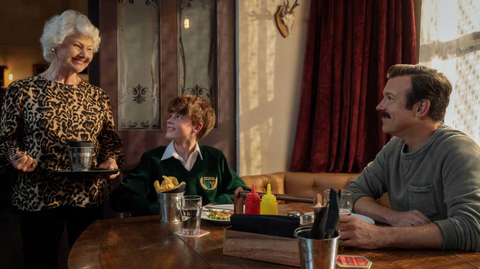 Mae Green serving Ted Lasso and his son Henry at her pub in season 4