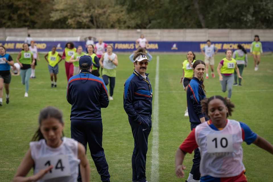Ted Lasso and coaches looking at Richmond's women's team