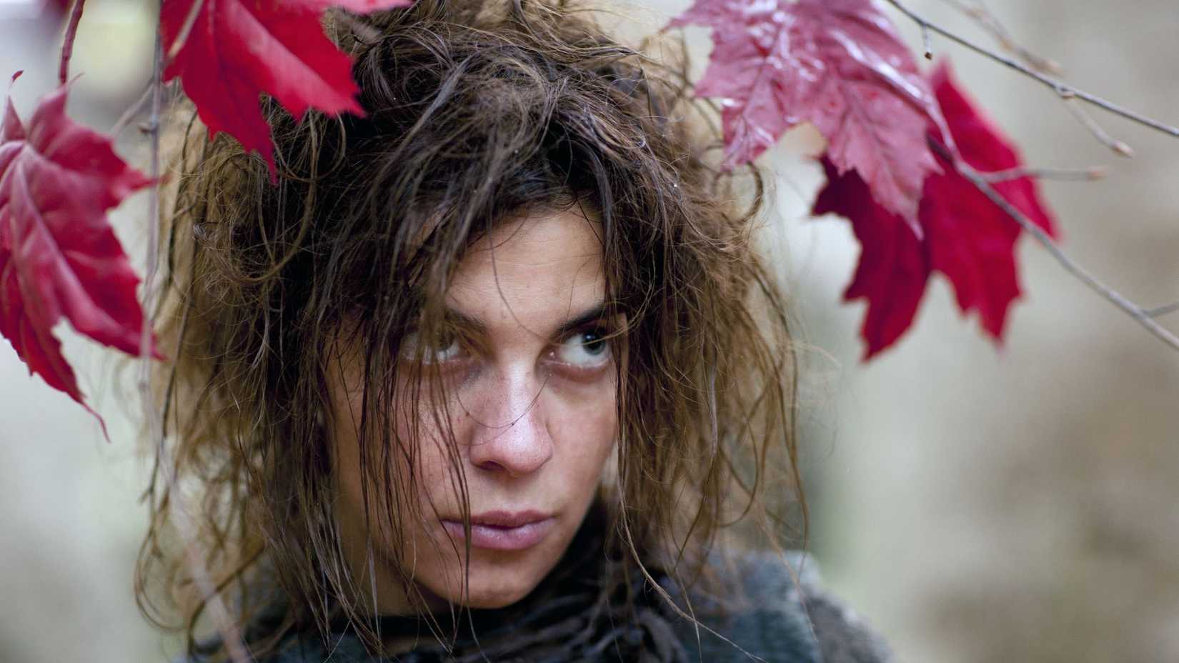 Osha (Natalia Tena) looking at someone from beneath a tree in Game of Thrones.