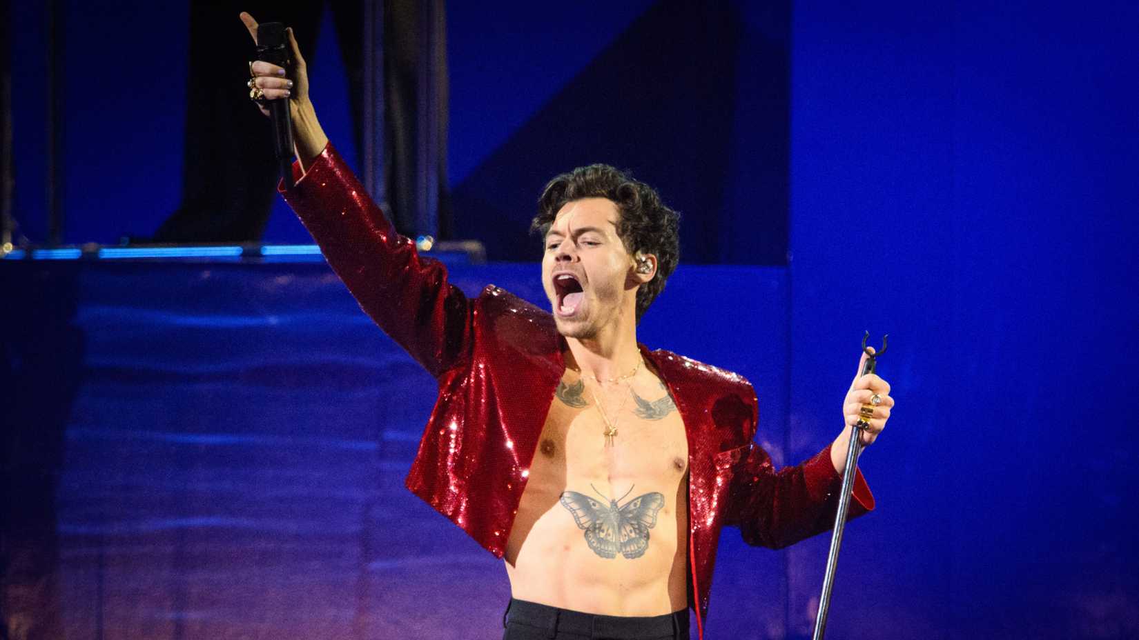 Harry Styles performing on stage in sparkly red jacket