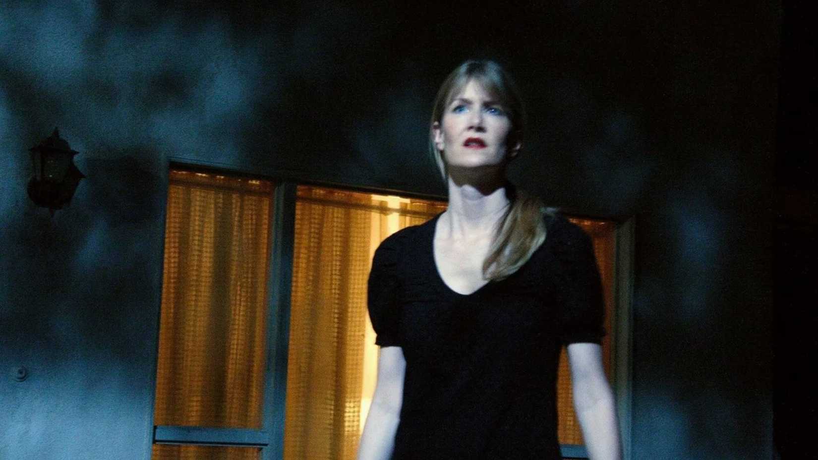 Laura Dern stands on a film set bathed in blue light in Inland Empire