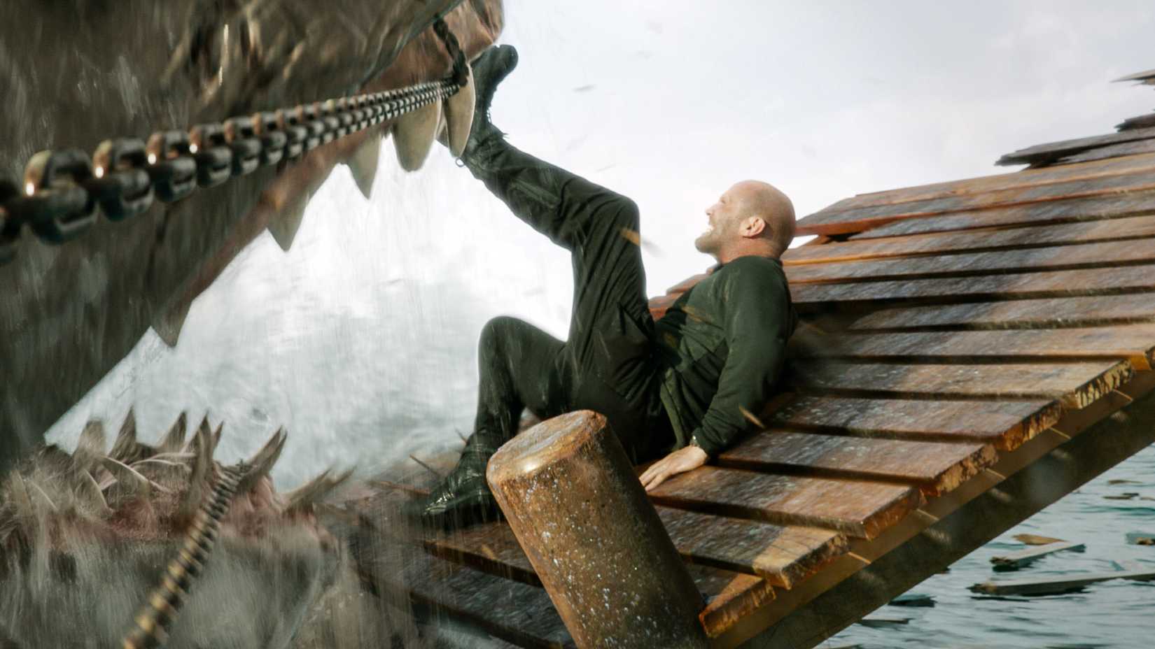Jason Statham holding a megalodon's jaws open with his leg in Meg 2 The Trench