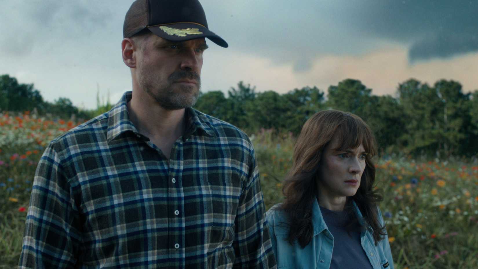 Jim Hopper e Joyce Byers em um campo, com expressão preocupada, no final da 4ª temporada de Stranger Things.