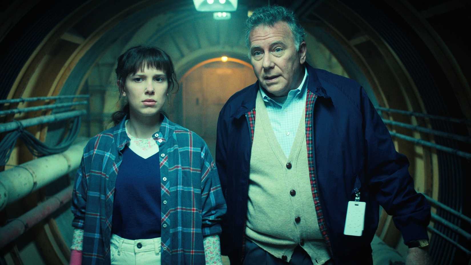 Millie Bobby Brown as Eleven and Paul Reiser as Dr. Owens walk through Project Nina.