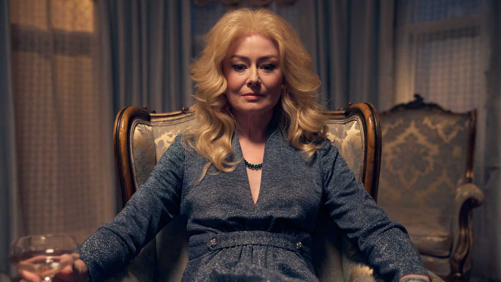 Miranda Otto as Adrienne Beaufort sitting in a chair with a drink in The Clearing