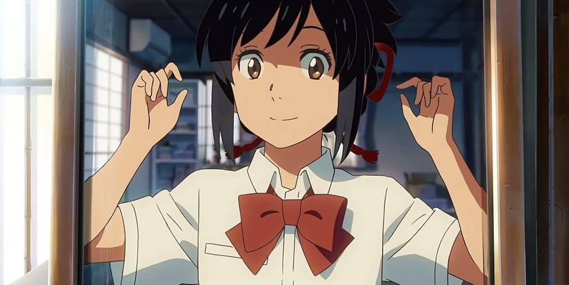 Mitsuha looks in the mirror while tying up her hair in Your Name
