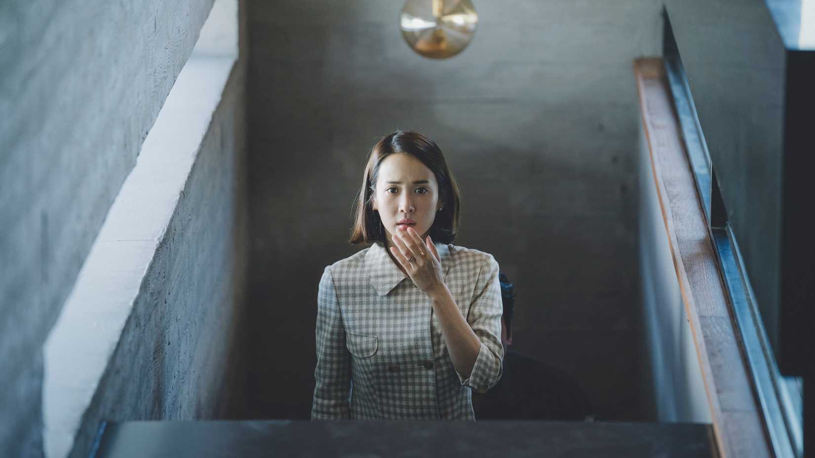 Mrs Park looking shocked at the top of the stairs in Parasite