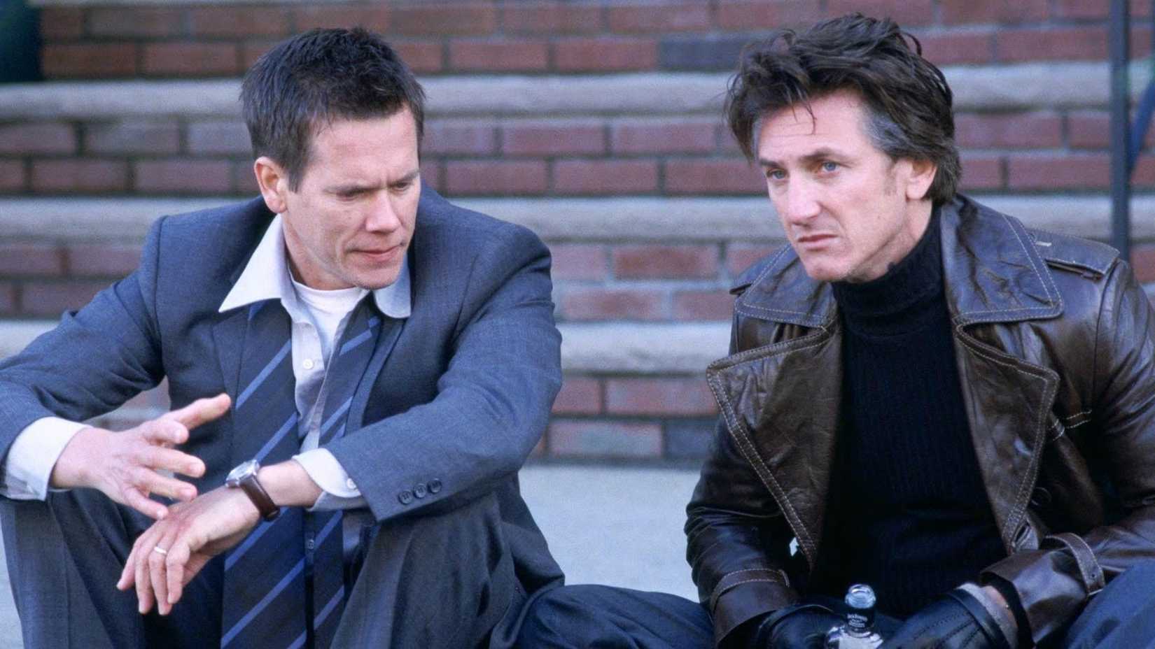Kevin Bacon and Sean Penn talk while sitting on the ground in Mystic River