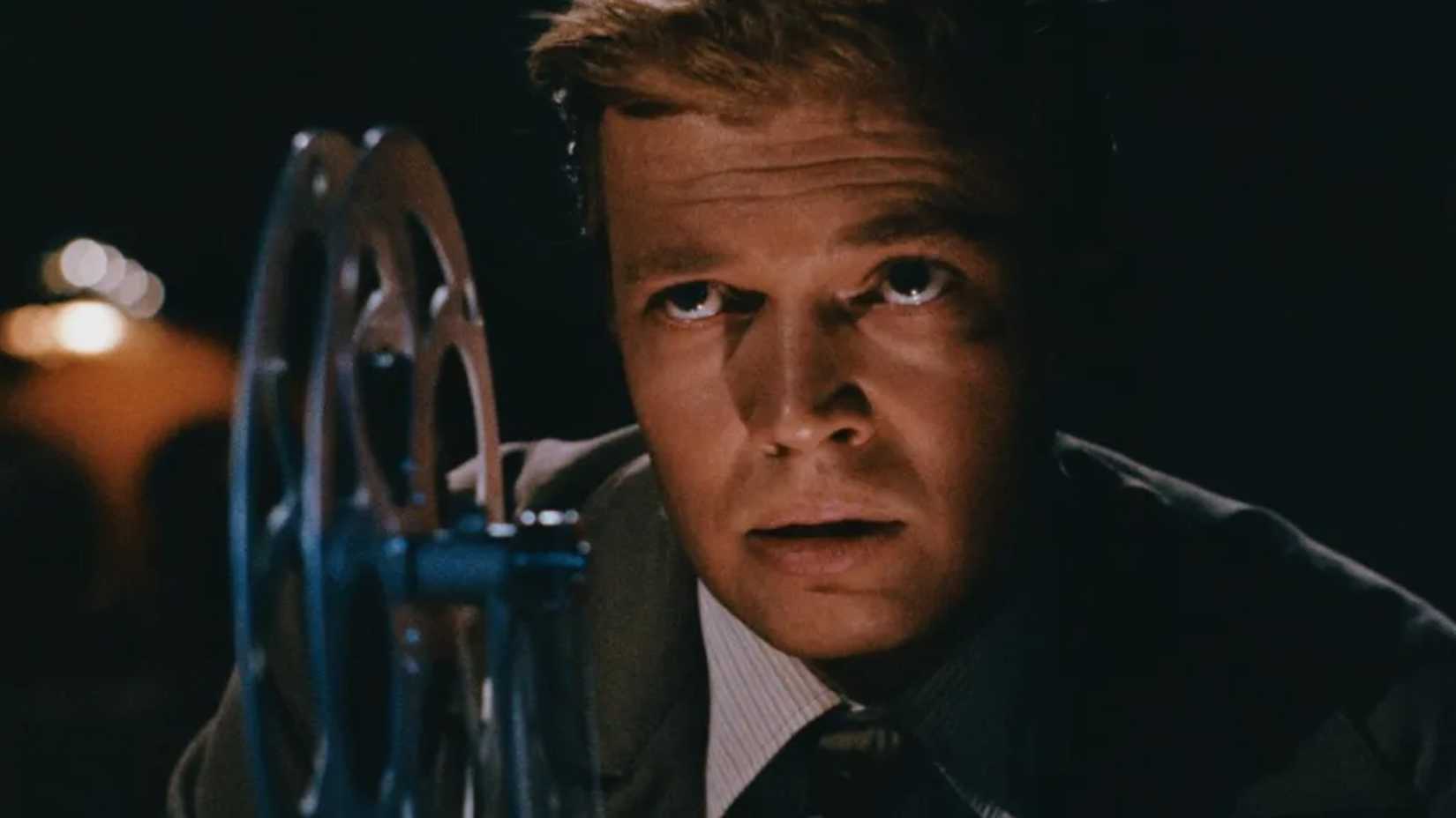 Mark looks over the reels of his projector in Peeping Tom