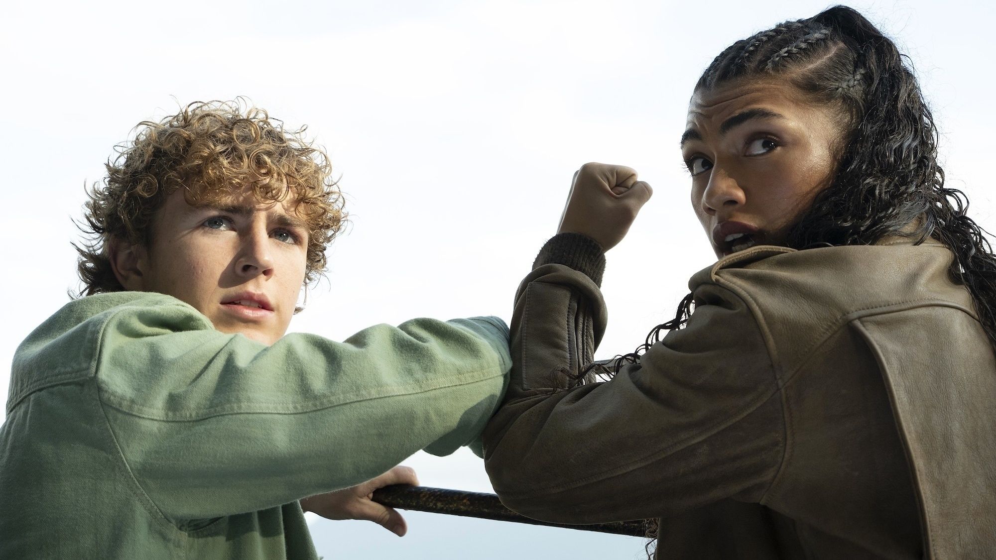 Percy Jackson (Walker Scobell) and Clarisse La Rue (Dior Goodjohn) looking over their shoulders with concern in Percy Jackson