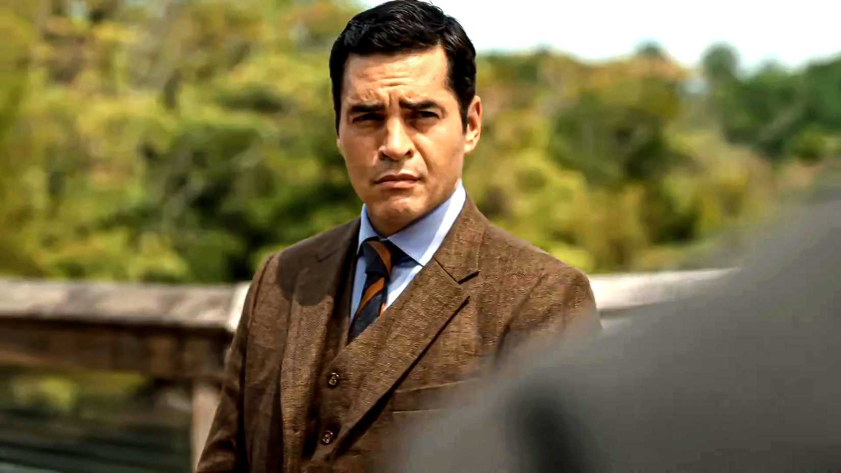 Ramón Rodriguez's Will looking suspiciously at someone in a sunny setting in Will Trent season 4