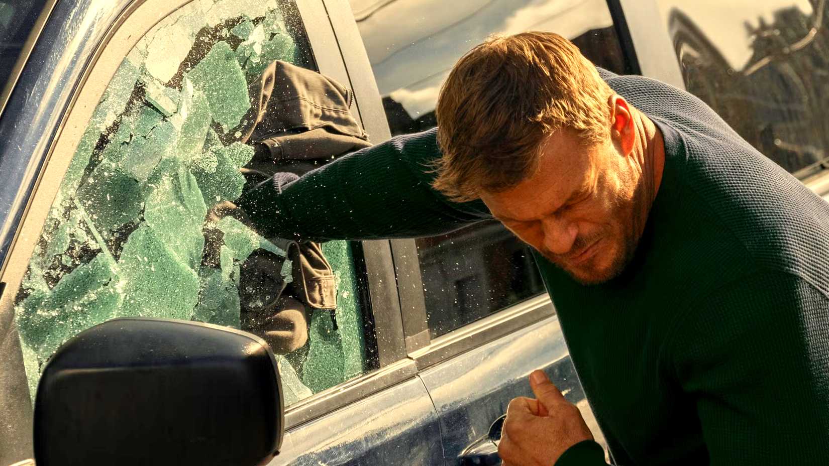 Alan Ritchson como Reacher quebrando janela de carro