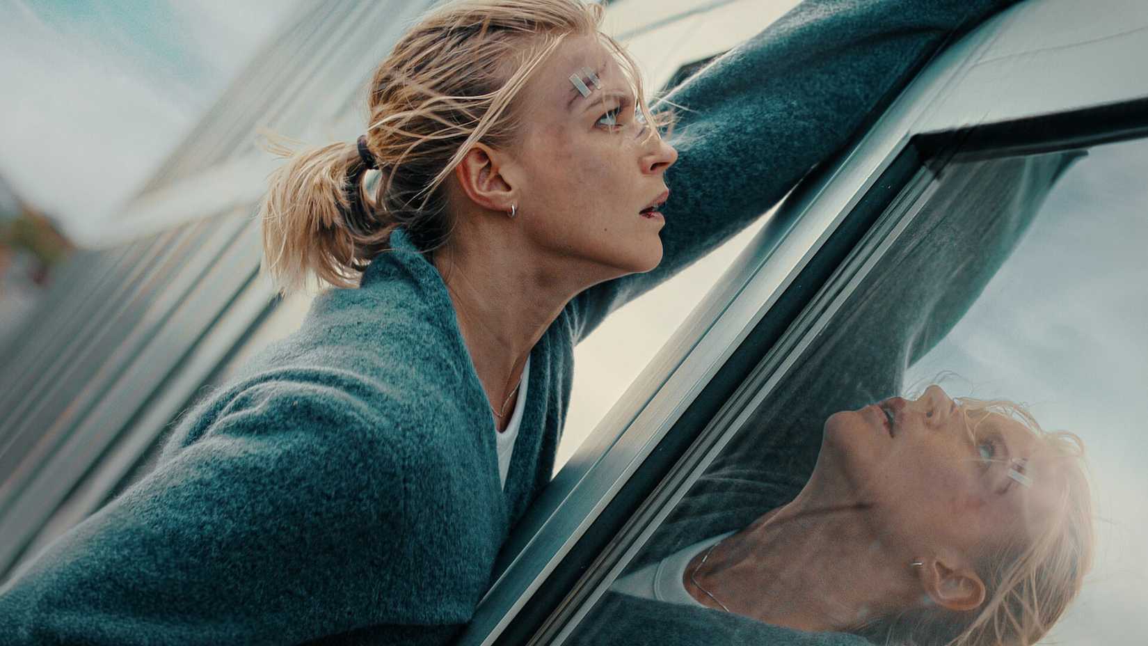 Sarah holding onto the side of a building in Exterritorial