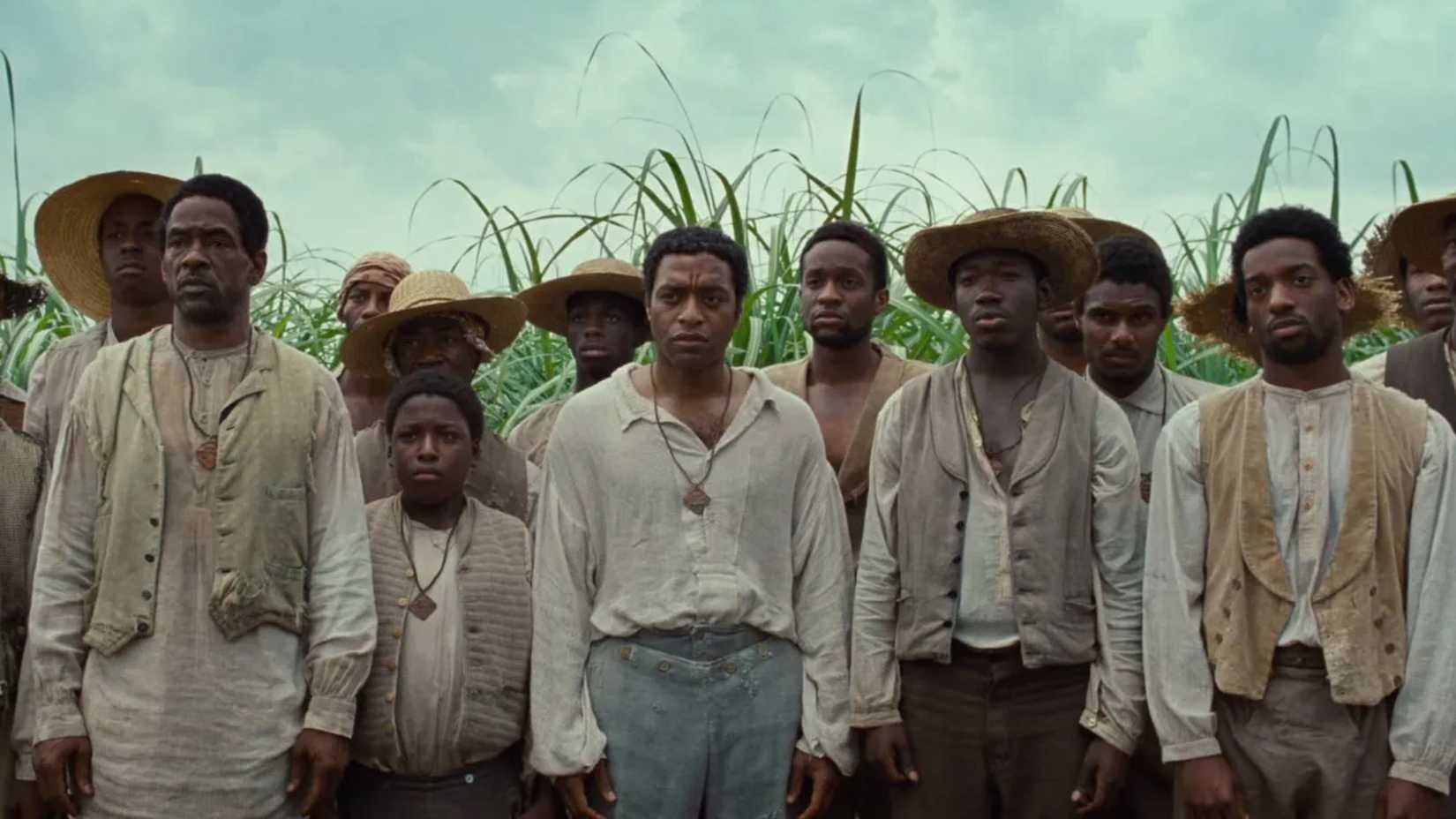 Solomon Northrup em um grupo de pessoas olhando para frente em 12 Anos de Escravidão