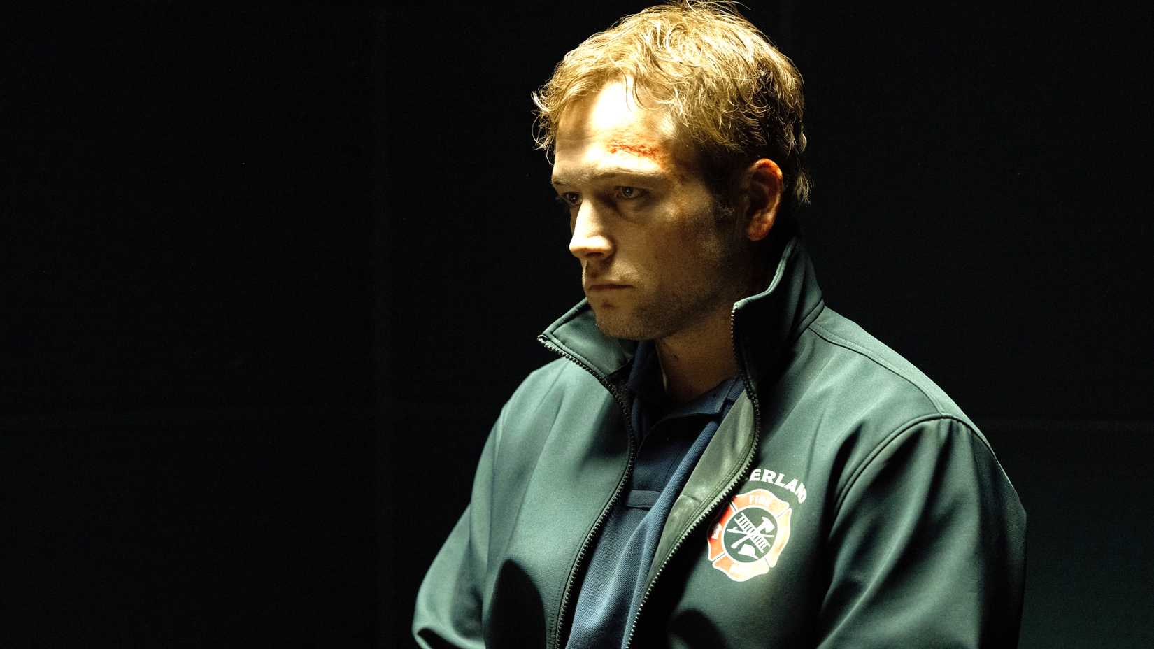 taron egerton s dave looking dejected while sitting at an interrogation table in smoke