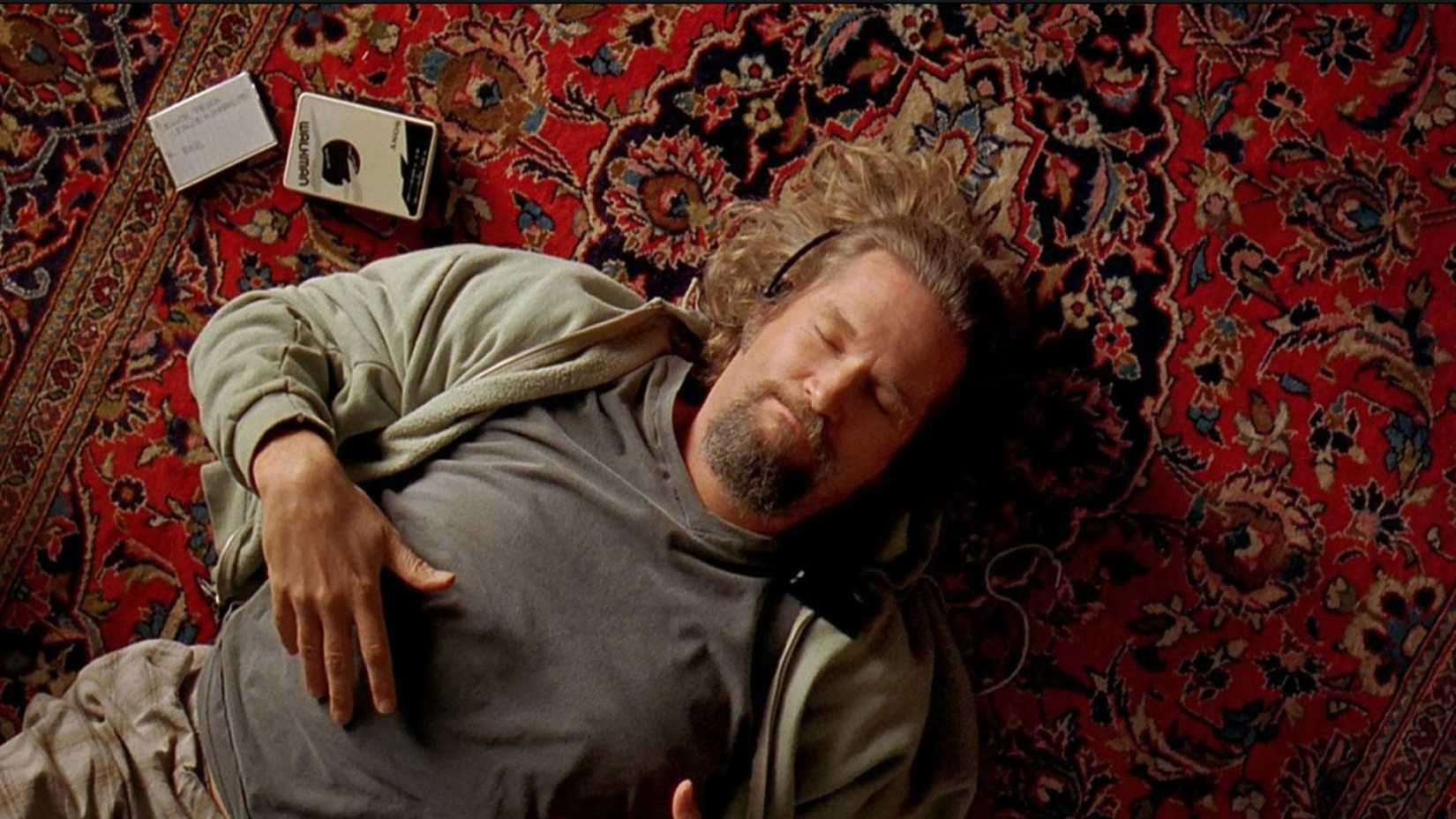 The Dude listens to a tape while laying on his rug in The Big Lebowski