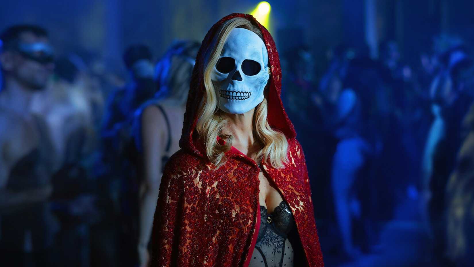 Uma mulher loira em uma capa vermelha e máscara de caveira em The Fall of The House of Usher da Netflix.