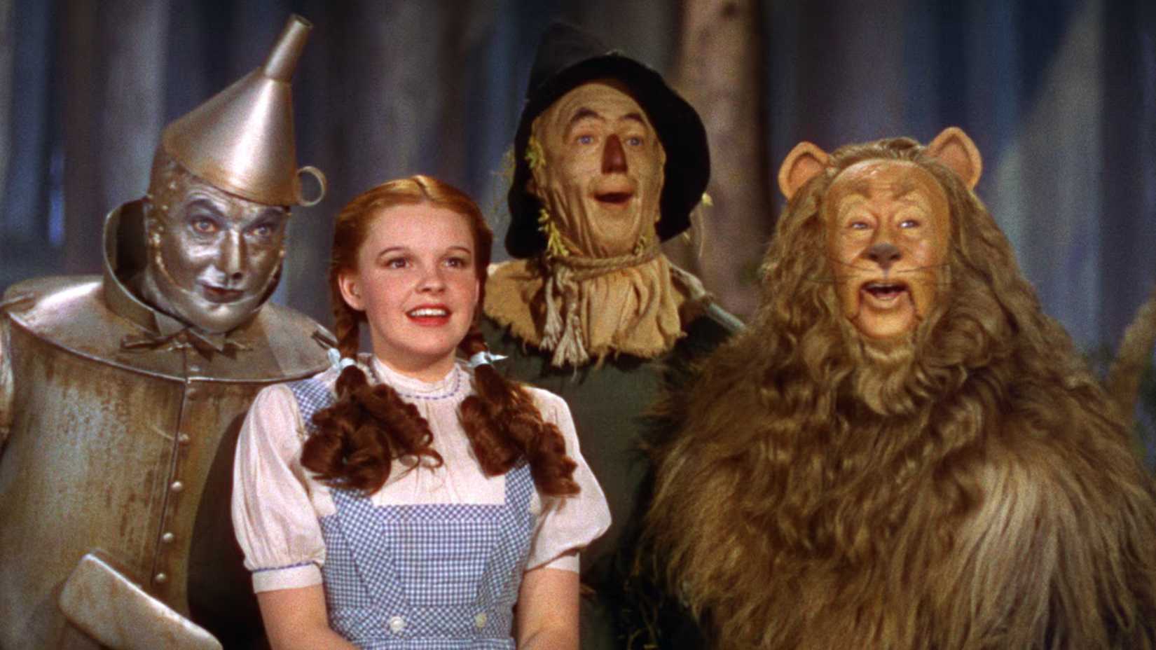 Dorothy, o Homem de Lata, o Espantalho e o Leão Covarde sorriem em O Mágico de Oz