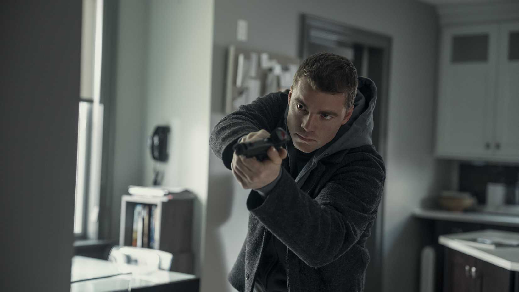 Peter (Gabriel Basso) apontando sua arma e olhando por cima do canto em The Night Agent