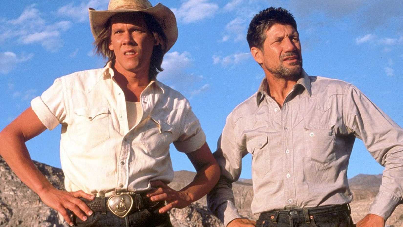 Fred Ward and Kevin Bacon stand with their hands on their hips in Tremors