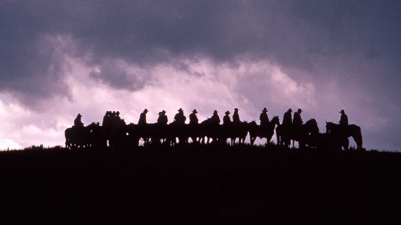 Silhouette of horse riders on a dark hill against the sky in Lonesome Dove (1989)
