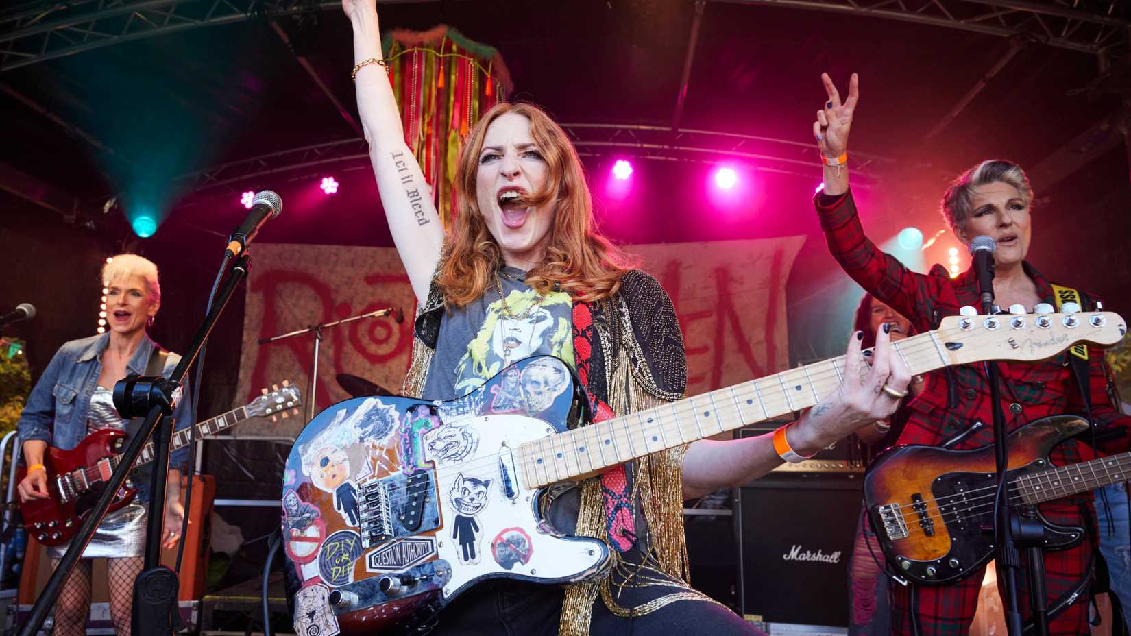 Yvonne, Helen, and Kitty on stage with their guitars in Riot Women