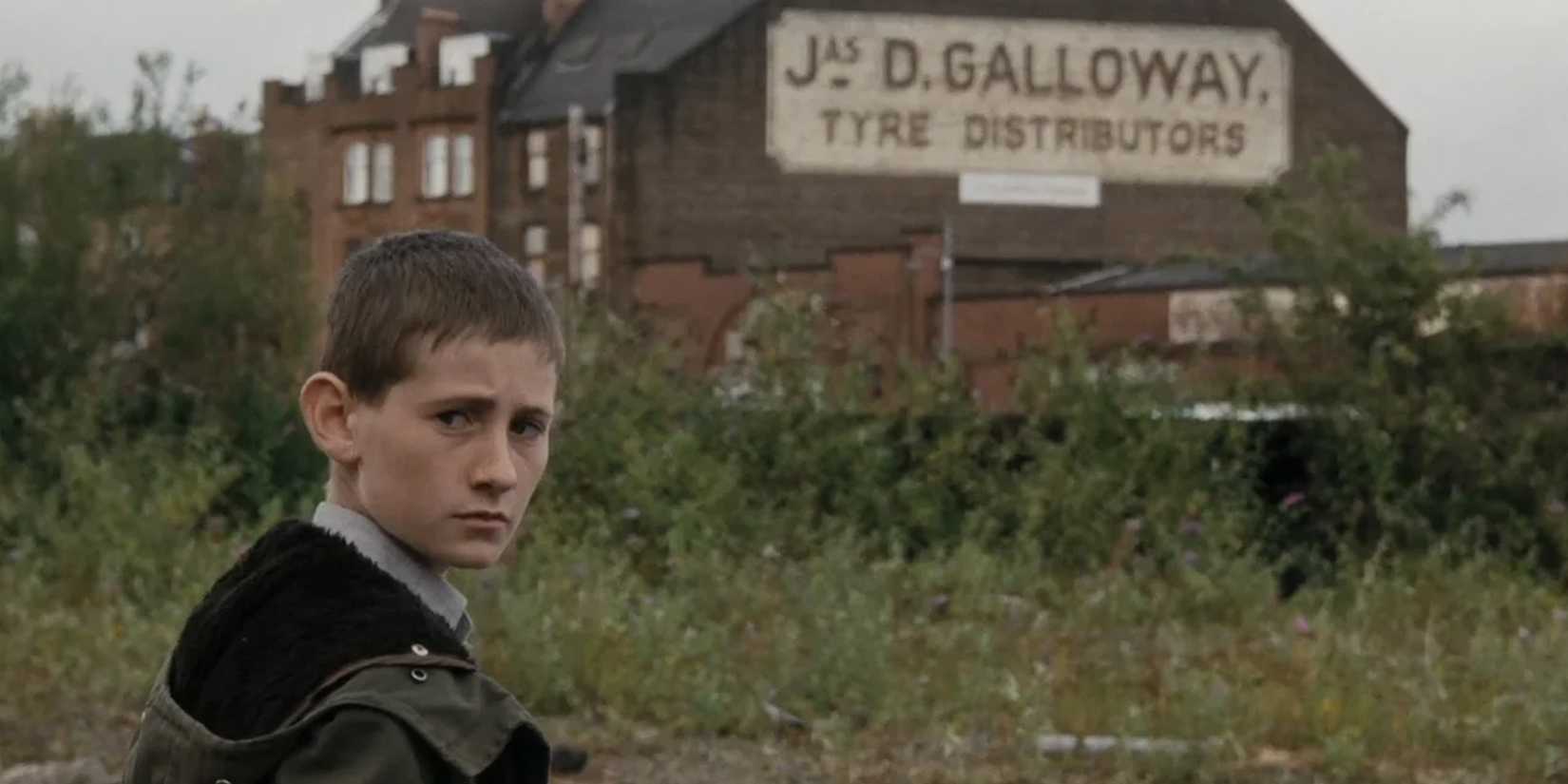 Um menino em pé perto de uma fábrica em Ratcatcher