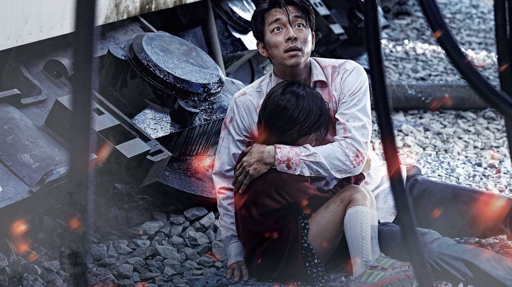 a man puts his arm around a scared child in train to busan