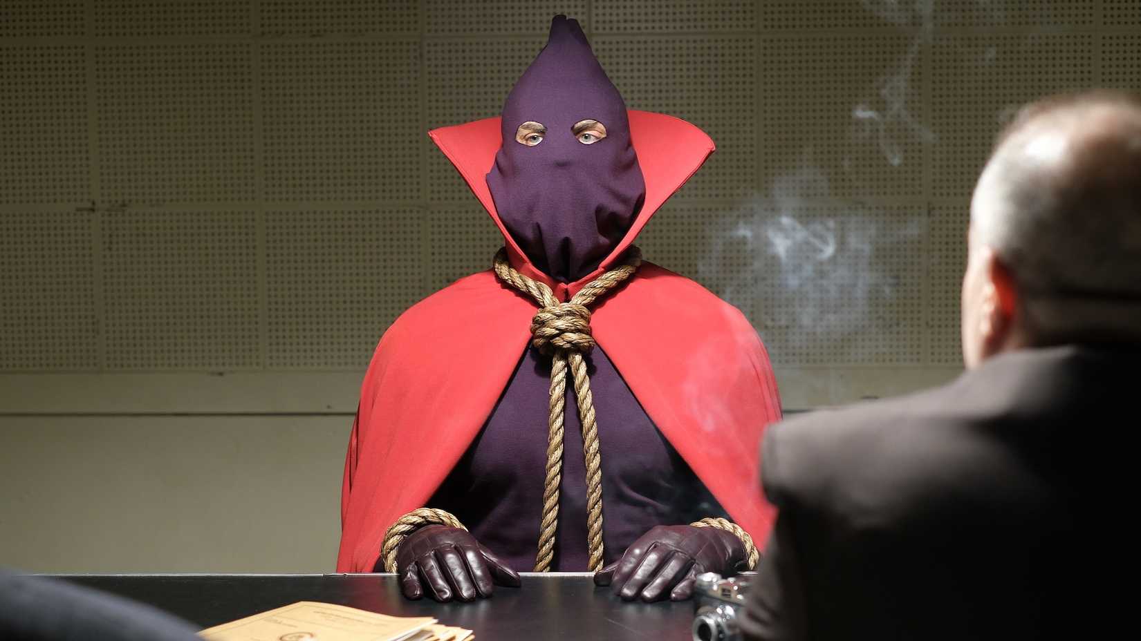 A masked vigilante in an interrogation room in Watchmen