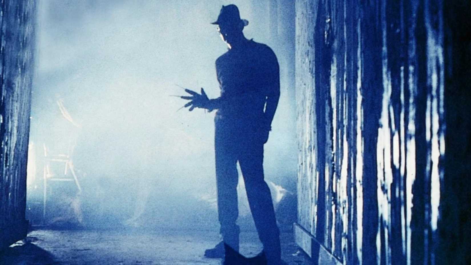 Freddy Krueger stands silhouetted in a dark hallway in A Nightmare On Elm Street