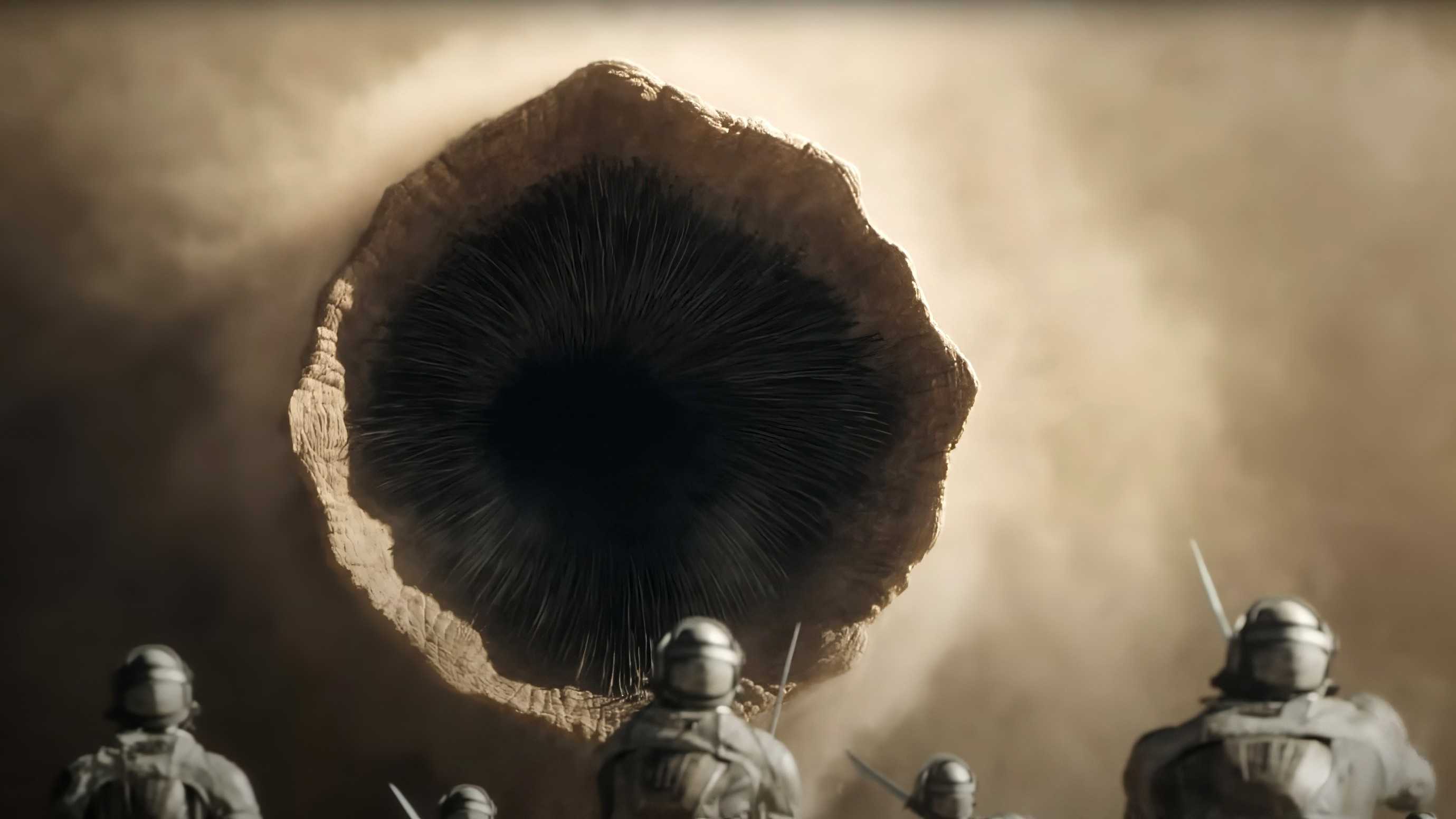 A sandworm emerges from the dust as Sardaukar look up at it in Dune Part 2