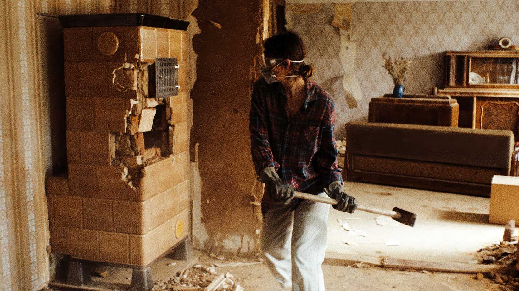 Una joven con una máscara demolir una habitación con un martillo en Sound of Falling