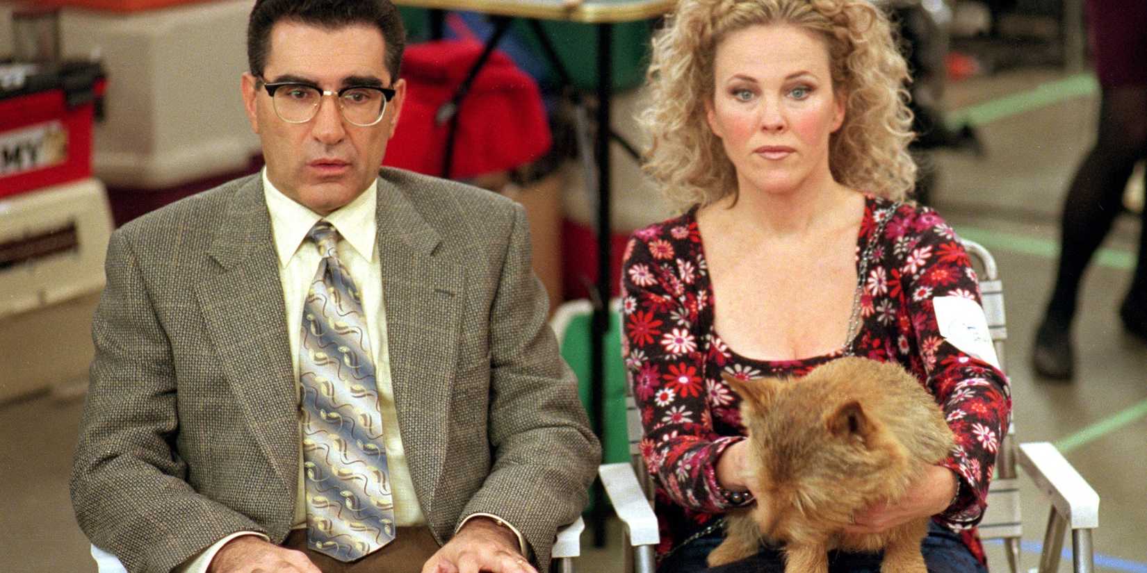 Eugene Levy and Catherine O'Hara sit with their dog and look off camera in Best in Show