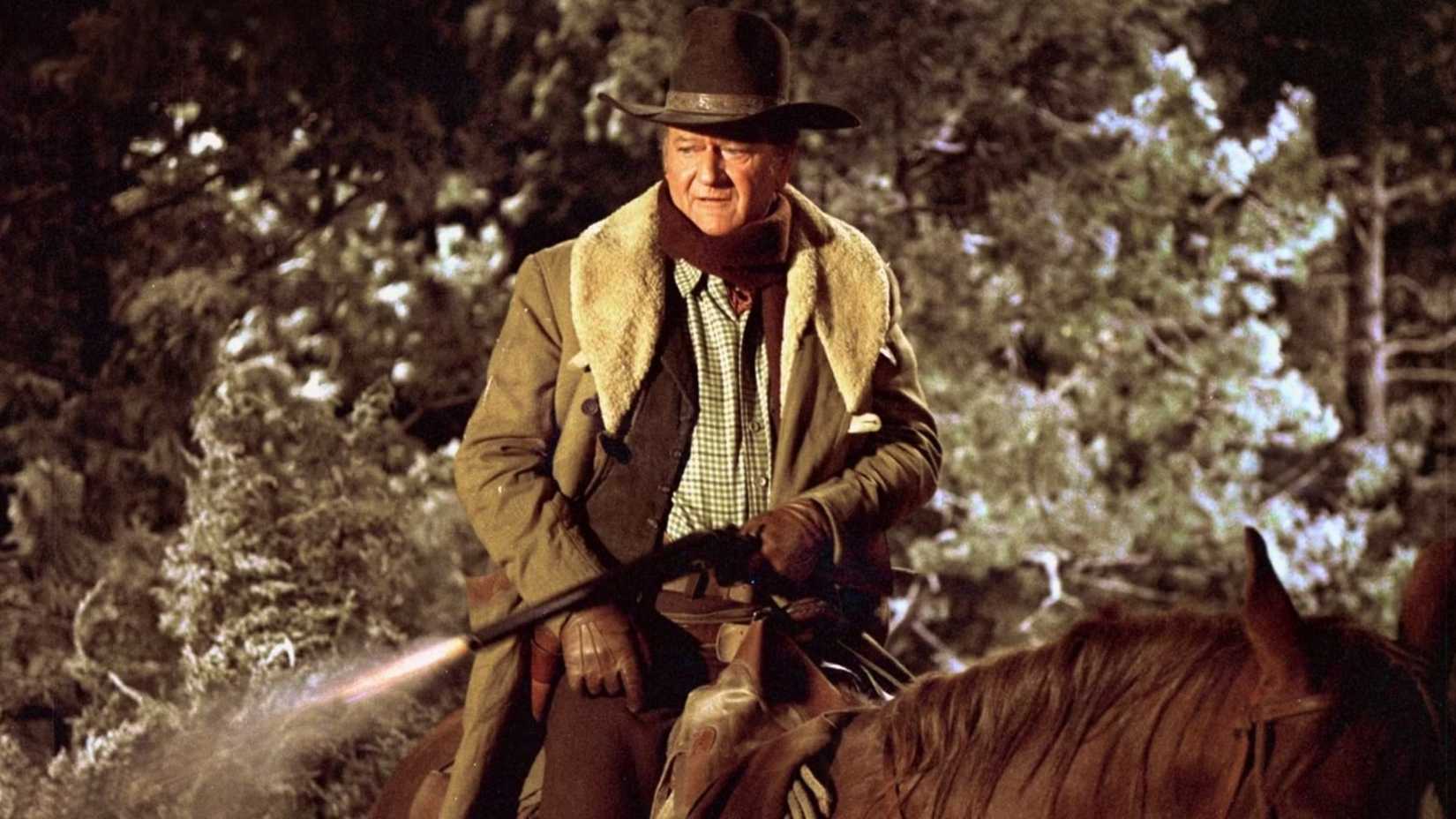 John Wayne dispara sua arma montado em um cavalo em Cahill US Marshall