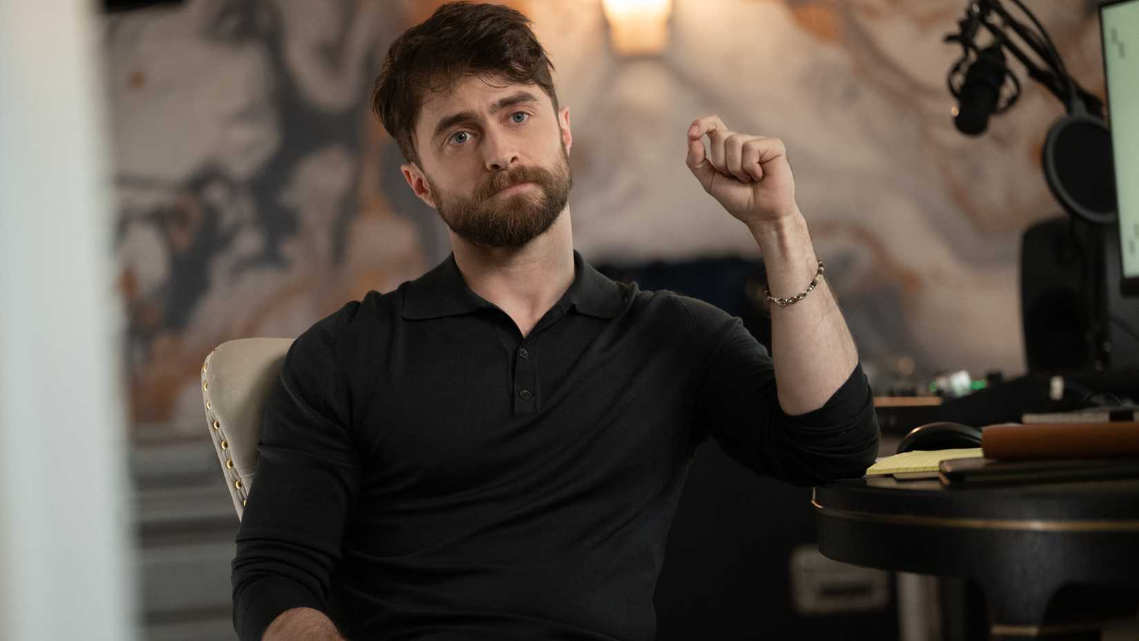 daniel radcliffe s arthur looking intense while sitting at his desk in the fall and rise of reggie dinkins