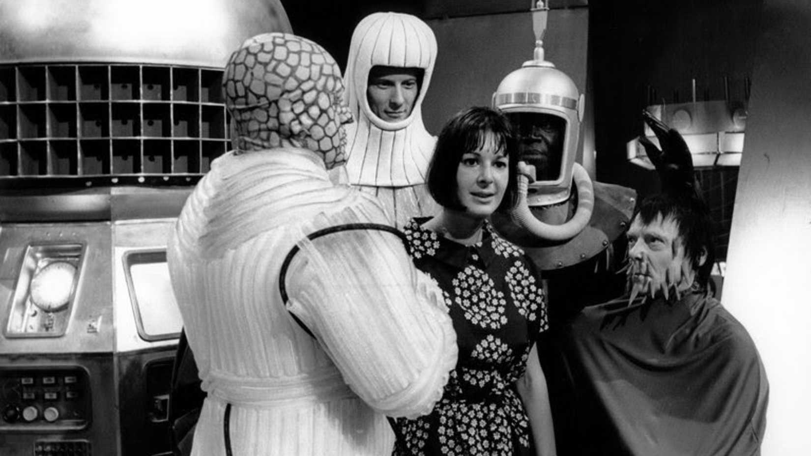 Женщина смотрит, окруженная инопланетянами в "Миссия в Неизвестность" из "Доктора Кто"