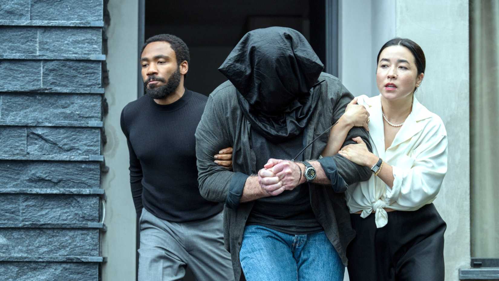 Donald Glover and Maya Erskine with a hooded man in Mr. & Mrs. Smith