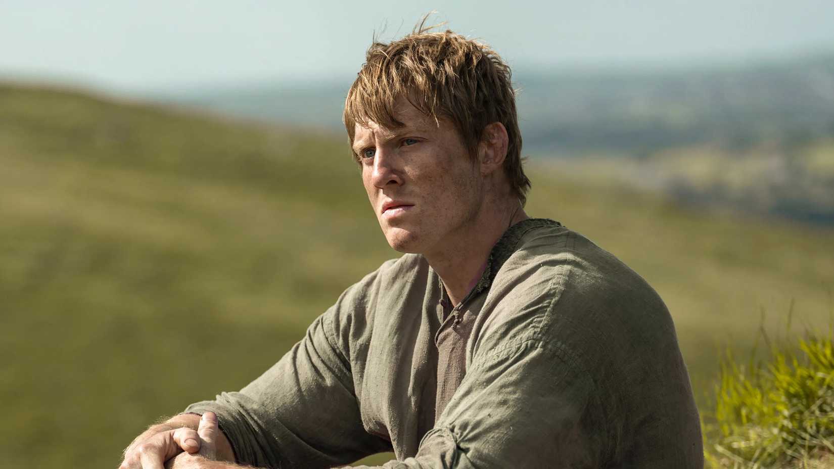 Dunk sentado em um campo em A Knight of the Seven Kingdoms