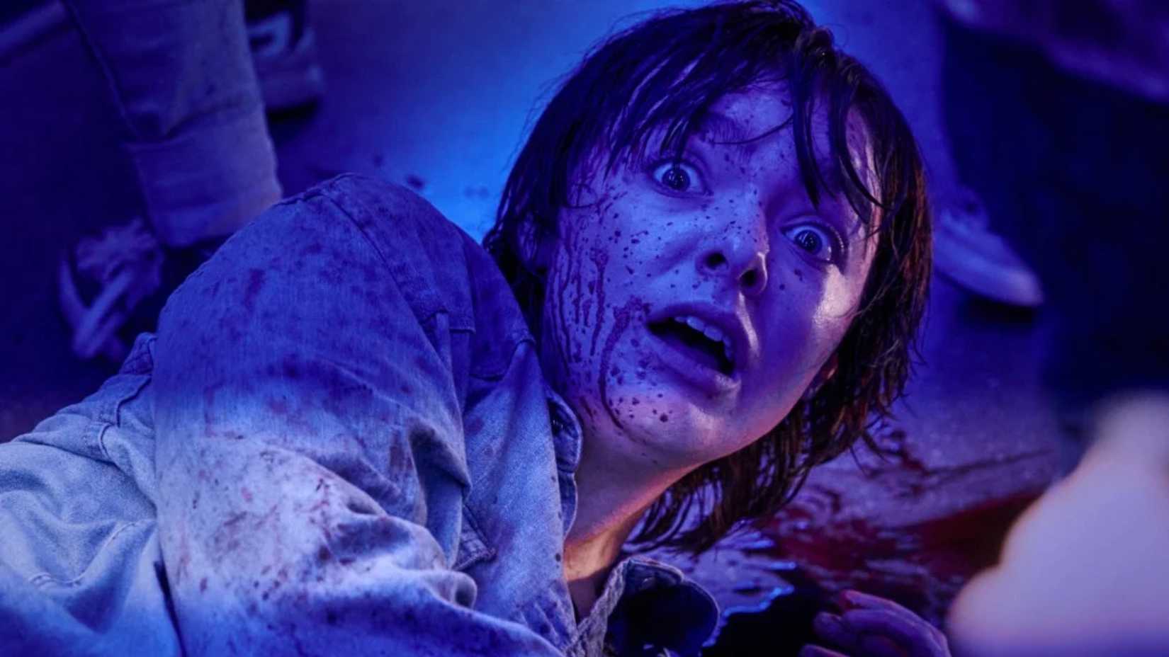 Elsie Fisher's face covered in blood while laying on the ground in Texas Chainsaw Massacre