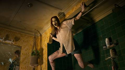 Evil Dead Rise Alyssa Sutherland as a Deadite hanging from the wall