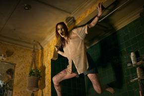 Evil Dead Rise Alyssa Sutherland as a Deadite hanging from the wall