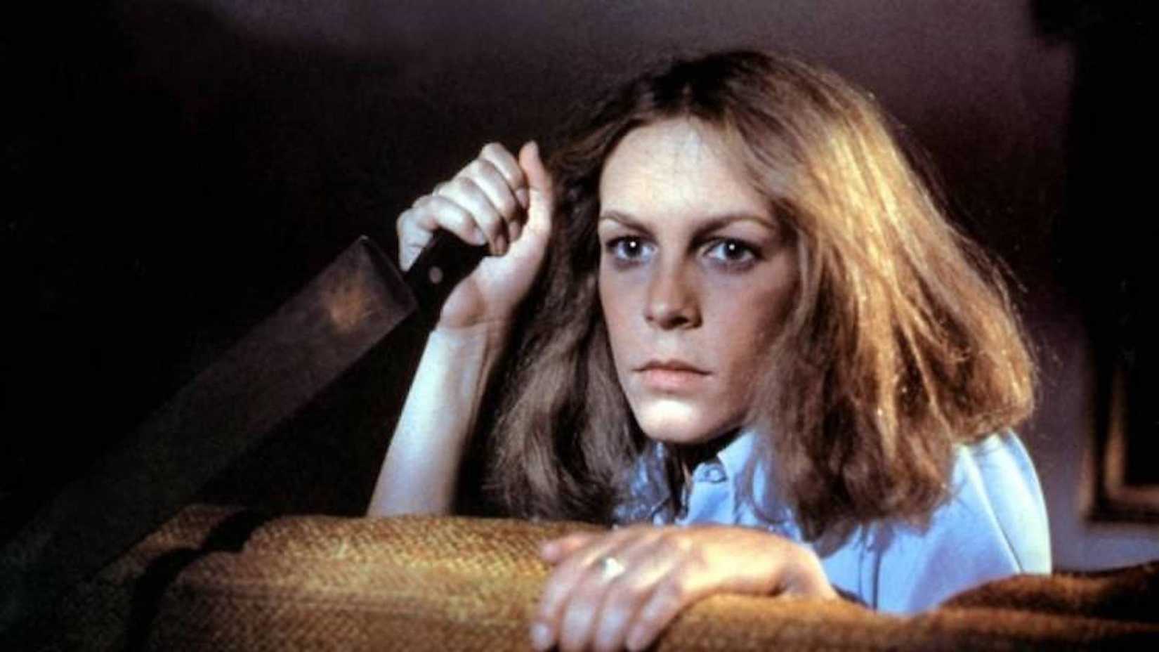 Jamie Lee Curtis holds a huge knife while looking on in Halloween