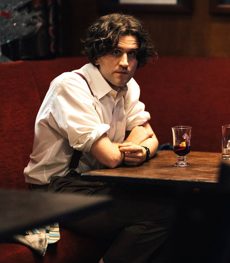 Harry Melling como Colin, com uma expressão surpresa em uma cabine em Pillion.