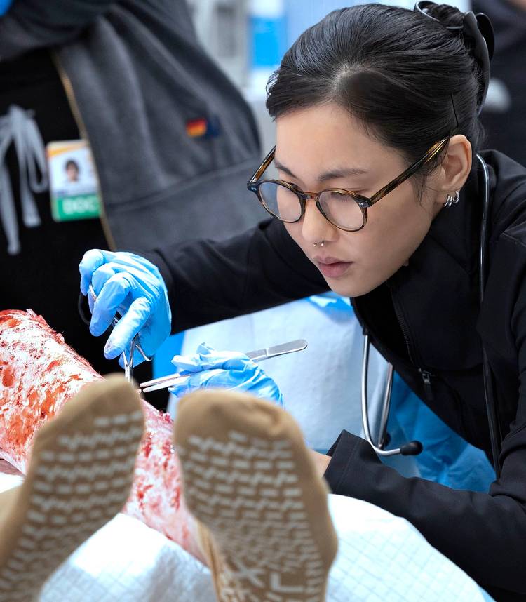 Dra. Kwon remove cuidadosamente cacos de vidro de uma perna ferida em The Pitt 2.